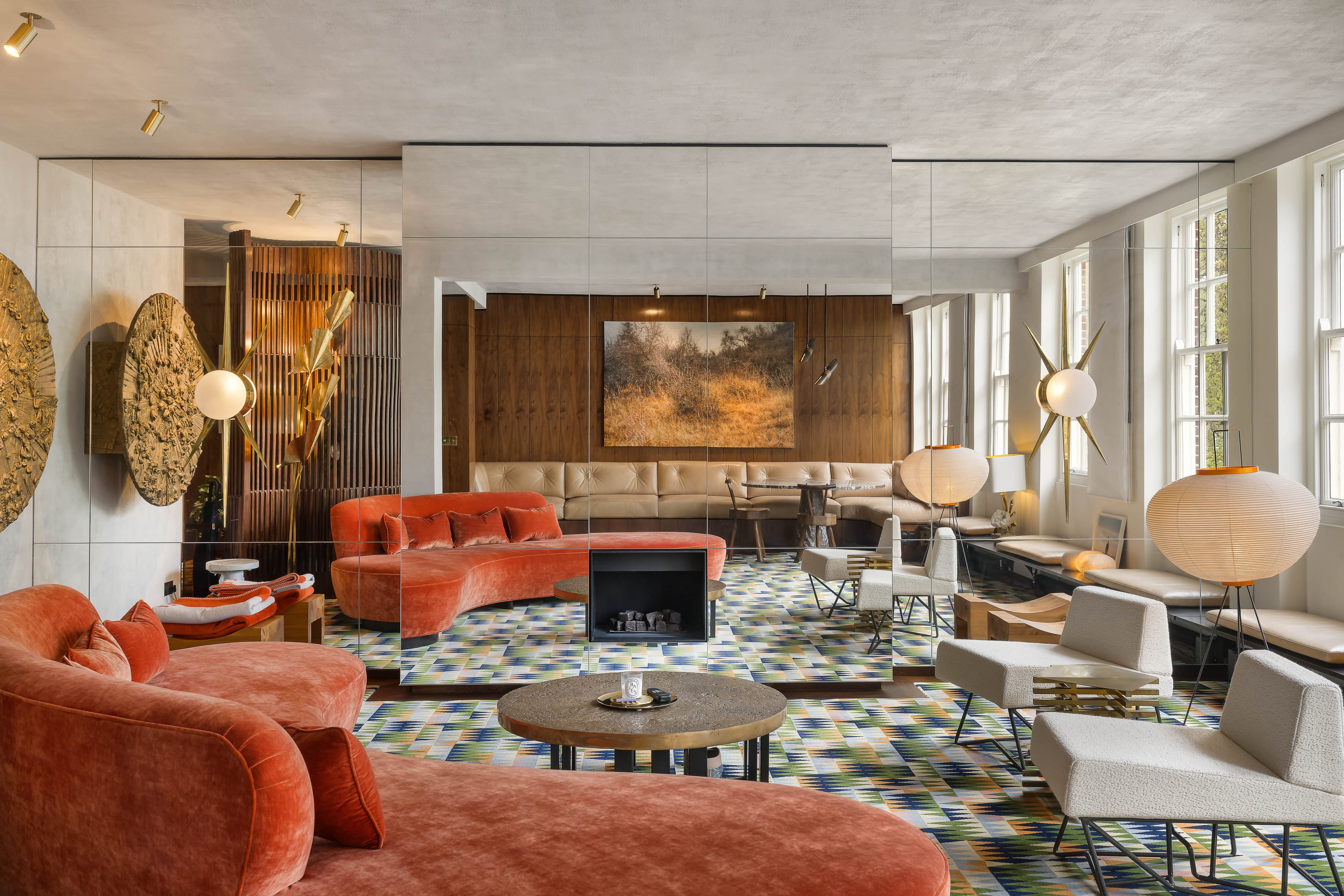 Interior of luxury Knightsbridge apartment designed by Studio KO, featuring coral velvet seating, mirrored walls, bespoke lighting, geometric patterned rug and full-height windows overlooking Lowndes Square.